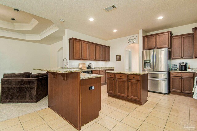 kitchen featuring crown molding, kitchen peninsula, light stone countertops, a raised ceiling, and stainless steel refrigerator with ice dispenser