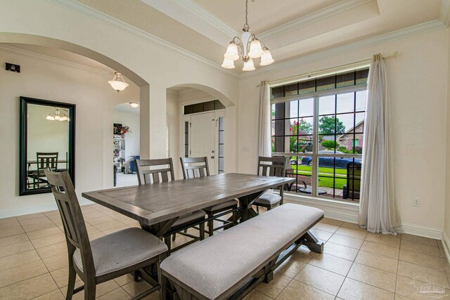 dining room with a raised ceiling, ornamental molding, light tile patterned floors, and an inviting chandelier