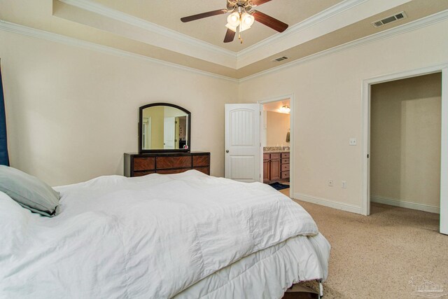 bedroom with a raised ceiling, ornamental molding, ensuite bath, and ceiling fan