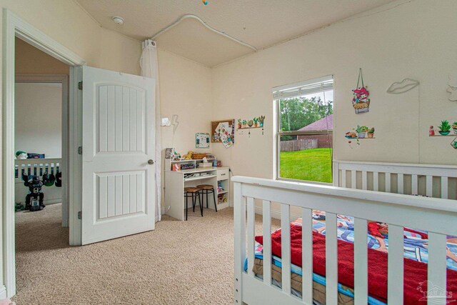 bedroom featuring light colored carpet and a nursery area