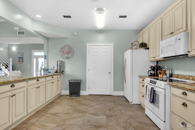 kitchen featuring cream cabinetry, light stone counters, and white appliances