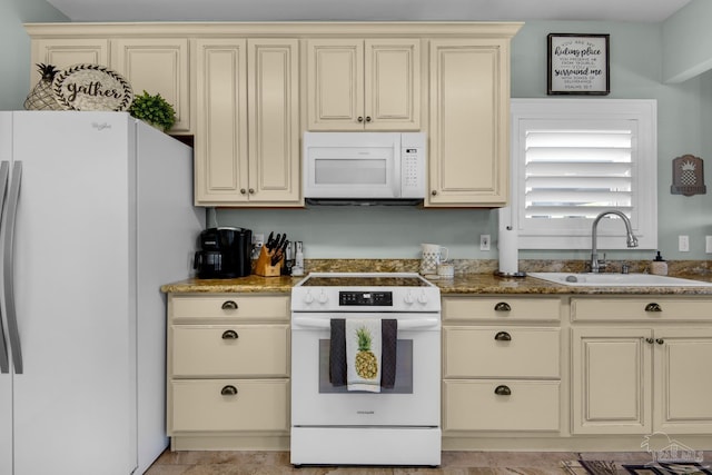 kitchen with sink, cream cabinetry, dark stone countertops, and white appliances