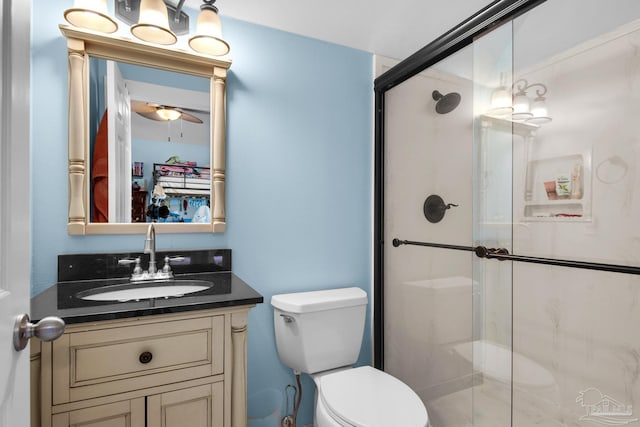 bathroom featuring toilet, a shower with door, and vanity