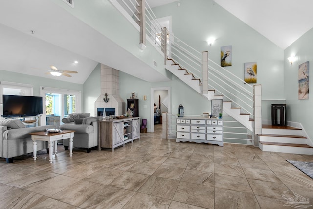 living room with high vaulted ceiling, ceiling fan, and a tile fireplace