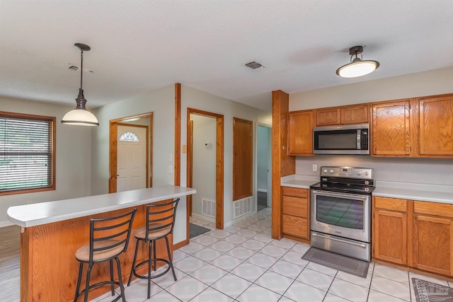 7026 Balboa Dr, Pensacola, FL 32526 - kitchen with appliances with stainless steel finishes, light countertops, brown cabinets, and a breakfast bar