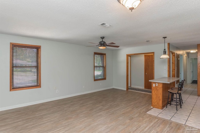 7026 Balboa Dr, Pensacola, FL 32526 - unfurnished living room featuring healthy amount of natural light, a textured ceiling, light wood-style flooring, and ceiling fan