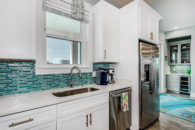 kitchen with wine cooler, stainless steel appliances, backsplash, white cabinets, and a sink