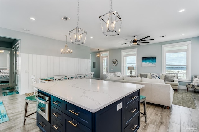 kitchen featuring visible vents, a kitchen breakfast bar, a center island, blue cabinetry, and stainless steel oven