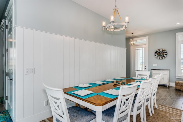 dining area with a chandelier, a wainscoted wall, and wood finished floors