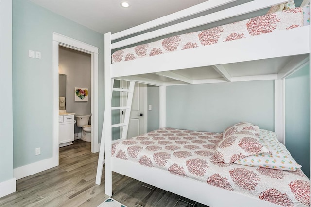 bedroom featuring recessed lighting, ensuite bathroom, baseboards, and wood finished floors