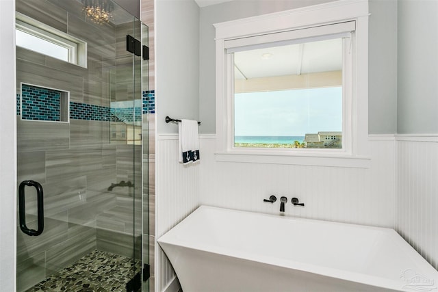 bathroom with a wainscoted wall, a freestanding tub, and a stall shower