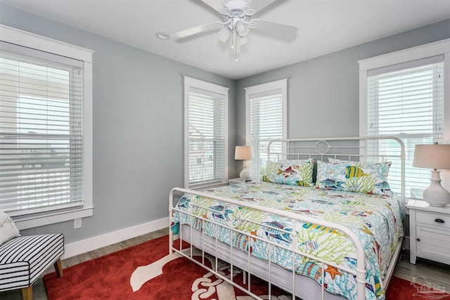 bedroom with multiple windows, baseboards, and wood finished floors