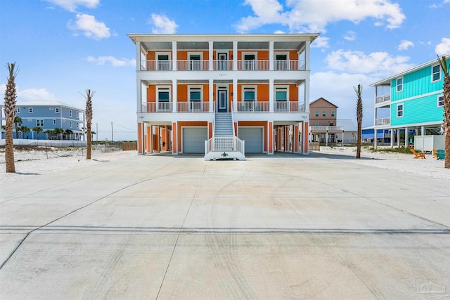 view of front of house with an attached garage, covered porch, stairs, and concrete driveway