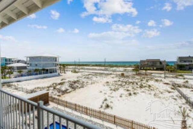 view of yard with a water view, fence, and a view of the beach