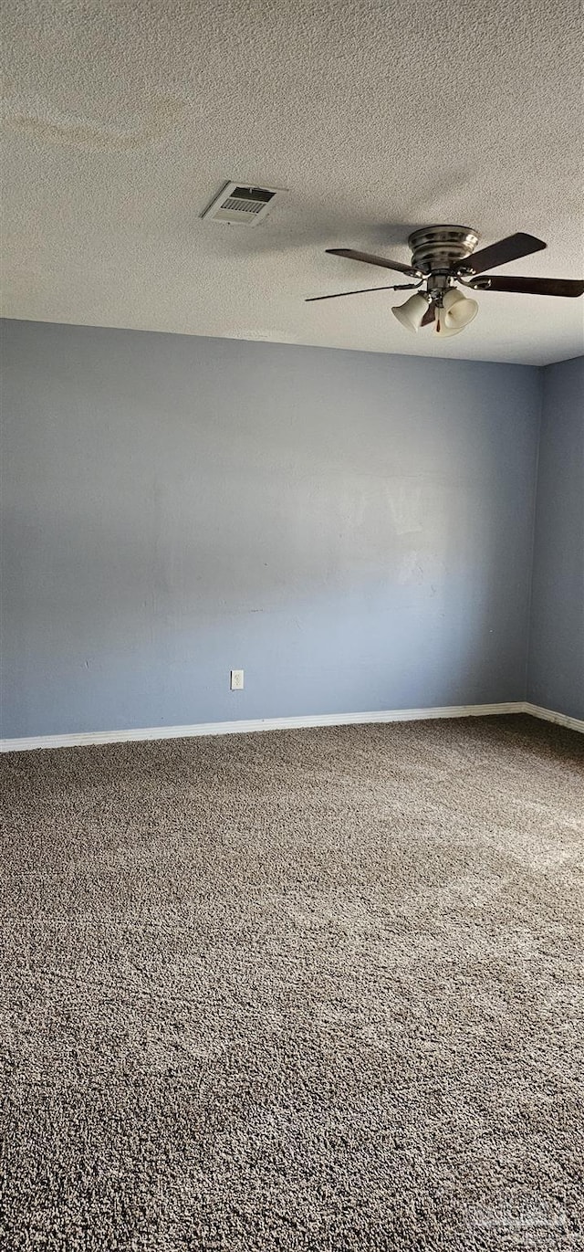 carpeted spare room with baseboards, a textured ceiling, visible vents, and a ceiling fan