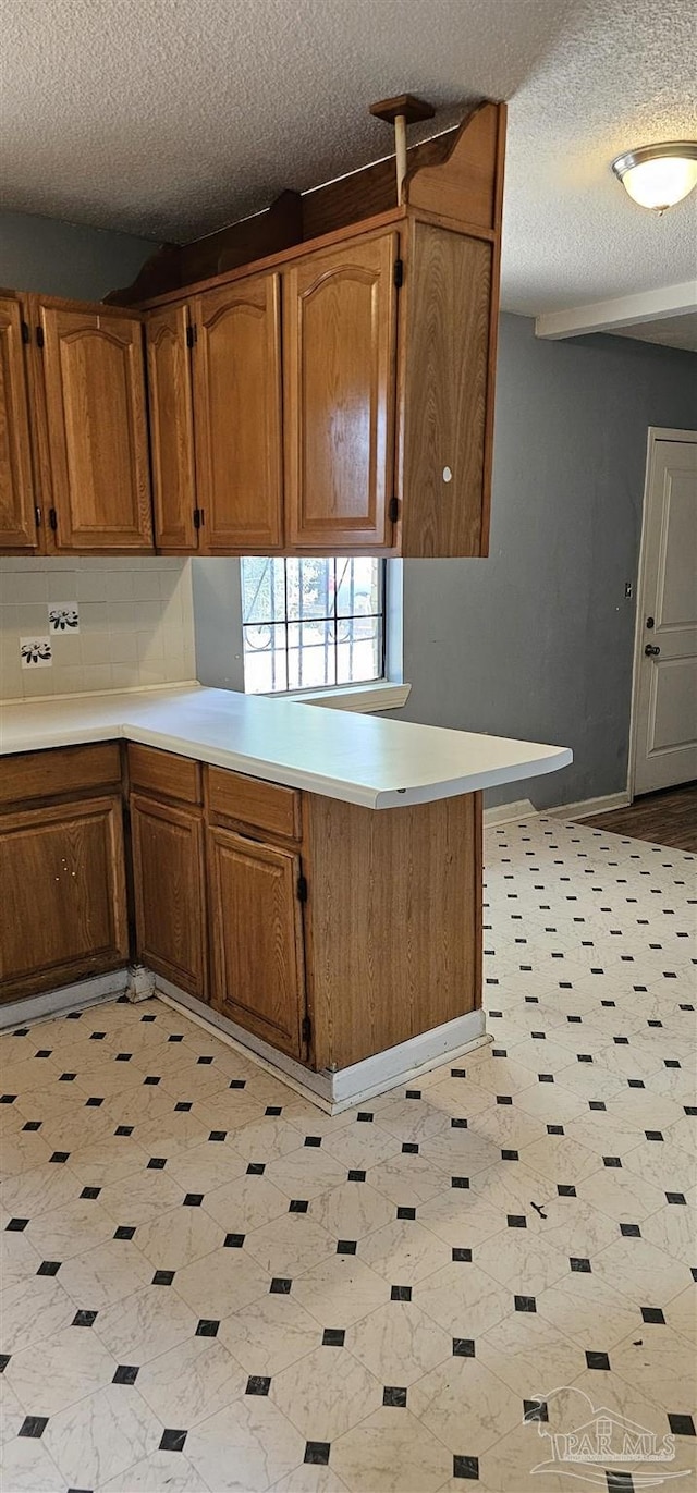 kitchen featuring backsplash, kitchen peninsula, and a textured ceiling