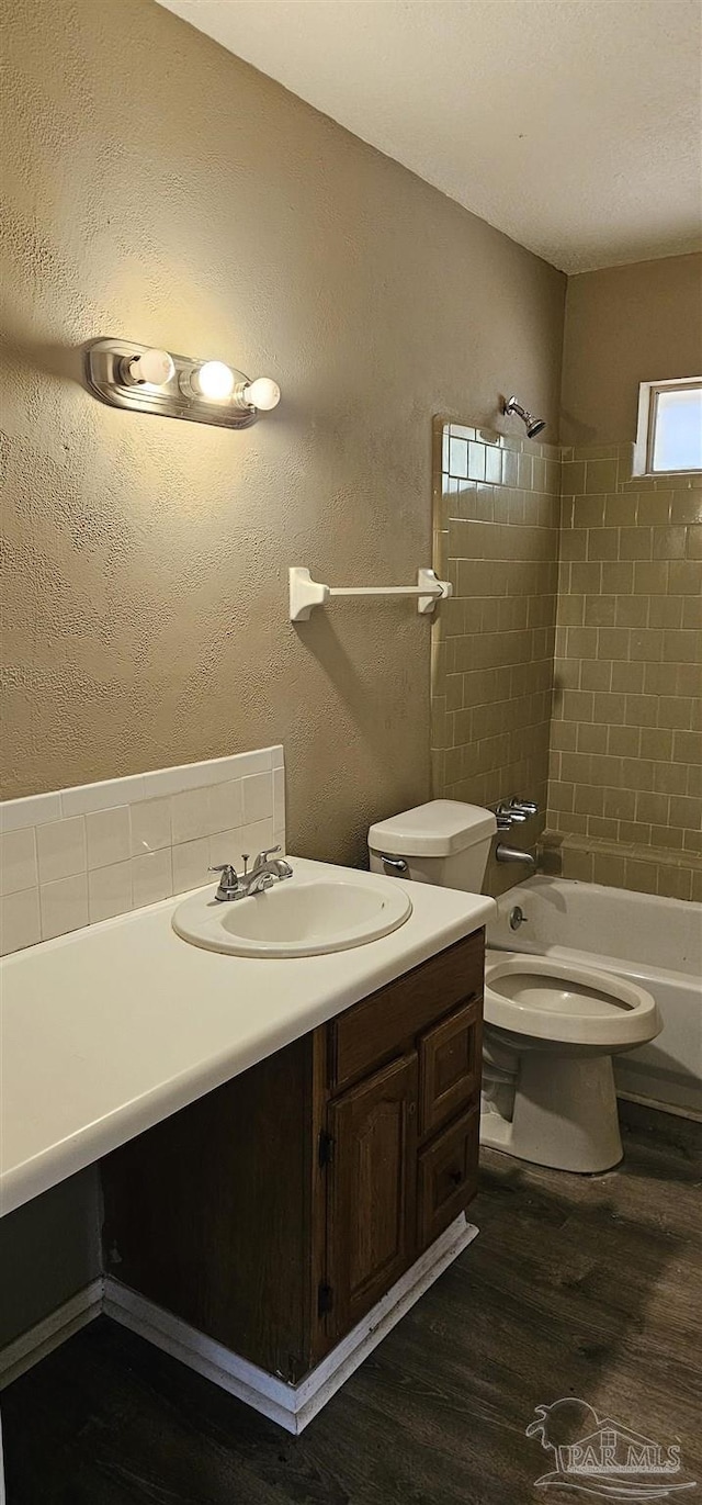 full bathroom featuring vanity, tiled shower / bath combo, hardwood / wood-style flooring, and toilet