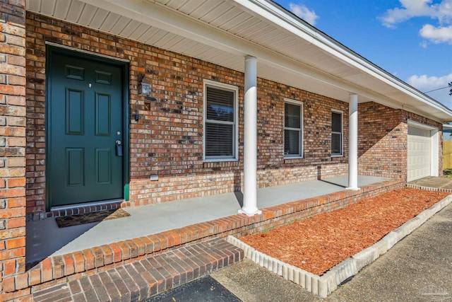 doorway to property with covered porch and a garage