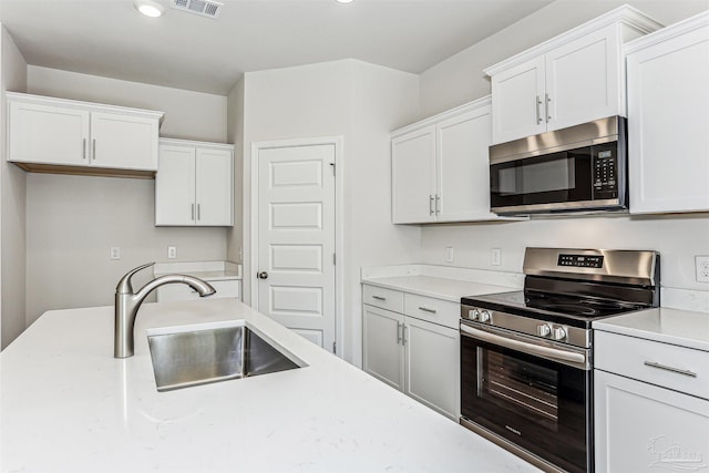 1644 Slate Dr, Cantonment, FL 32533 - kitchen with appliances with stainless steel finishes, a sink, light countertops, white cabinetry, and recessed lighting