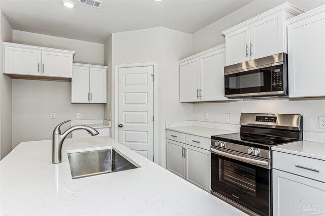 1644 Slate Dr, Cantonment, FL 32533 - kitchen with appliances with stainless steel finishes, a sink, light countertops, white cabinetry, and recessed lighting