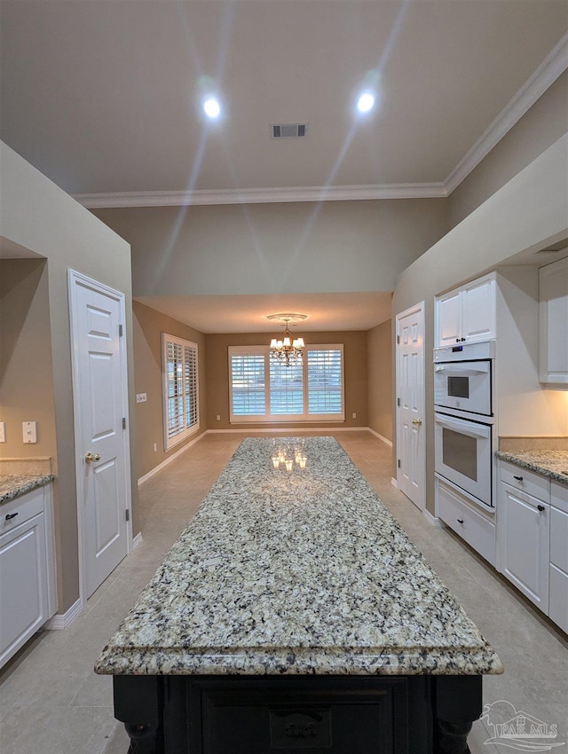 kitchen featuring white cabinets, an inviting chandelier, a healthy amount of sunlight, and crown molding