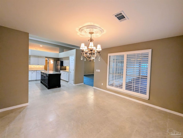 interior space featuring stainless steel refrigerator, a chandelier, a center island, and pendant lighting