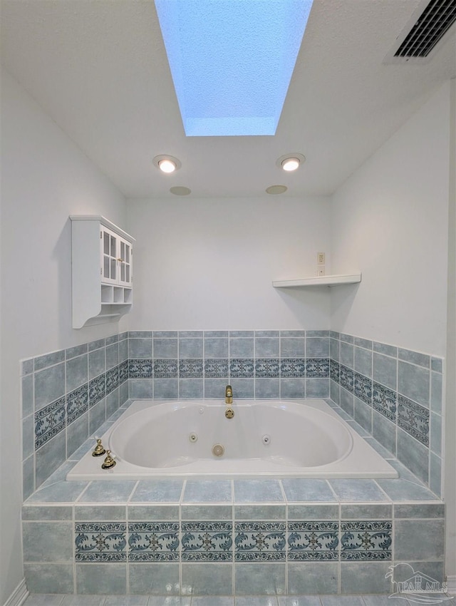 bathroom with a relaxing tiled tub and a skylight