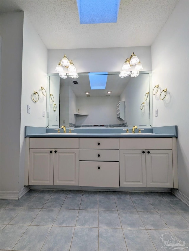 bathroom with vanity, a skylight, and tile patterned floors