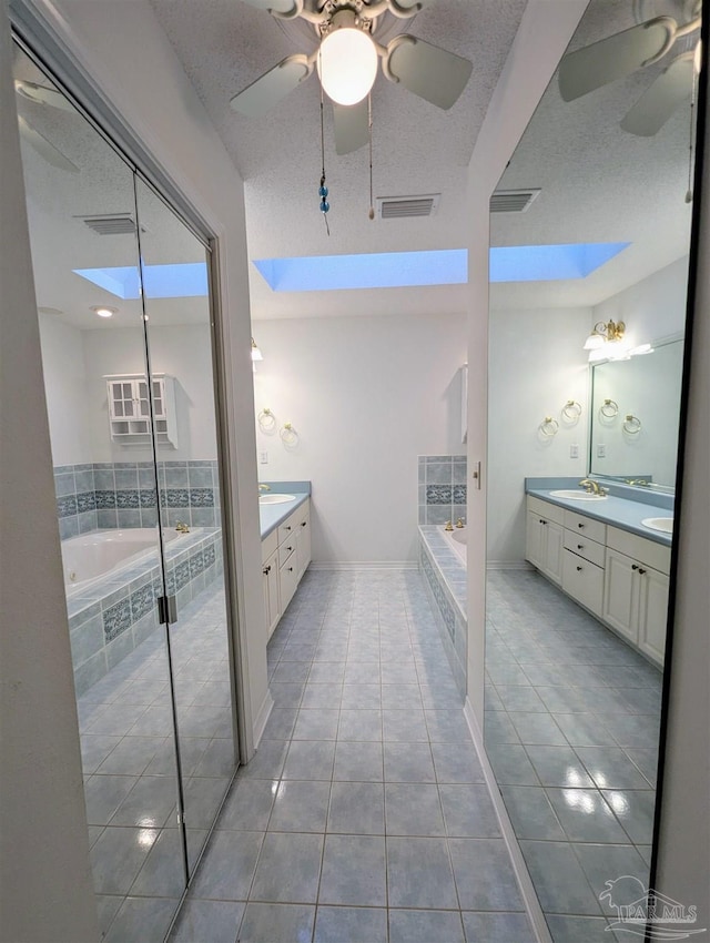 bathroom with vanity, a relaxing tiled tub, and tile patterned floors