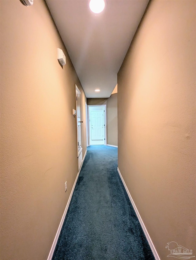 hallway featuring dark colored carpet