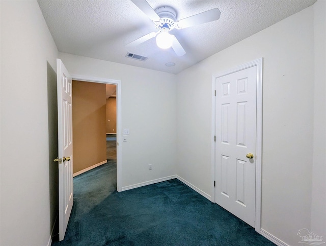 unfurnished bedroom with a textured ceiling, dark carpet, and ceiling fan