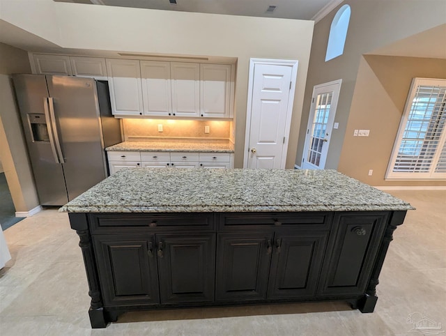 kitchen featuring stainless steel fridge with ice dispenser, light stone counters, and a kitchen island