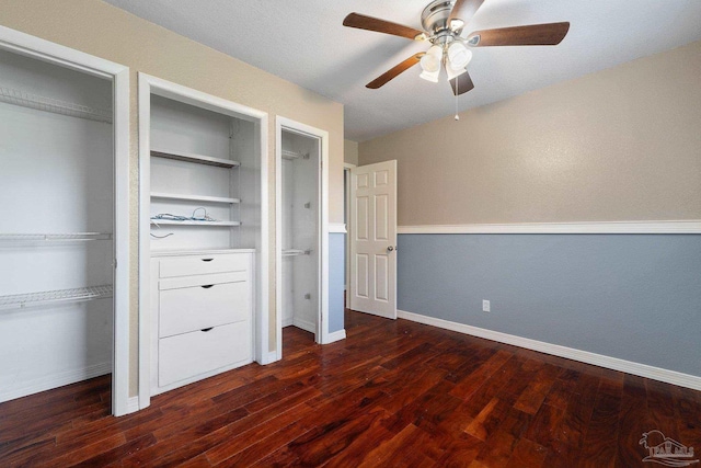 unfurnished bedroom with ceiling fan, a textured ceiling, dark hardwood / wood-style flooring, and multiple closets