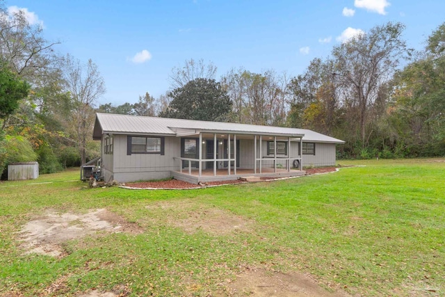 back of property with covered porch and a yard