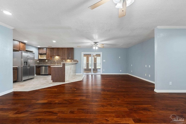 kitchen with hardwood / wood-style floors, appliances with stainless steel finishes, a textured ceiling, backsplash, and ceiling fan