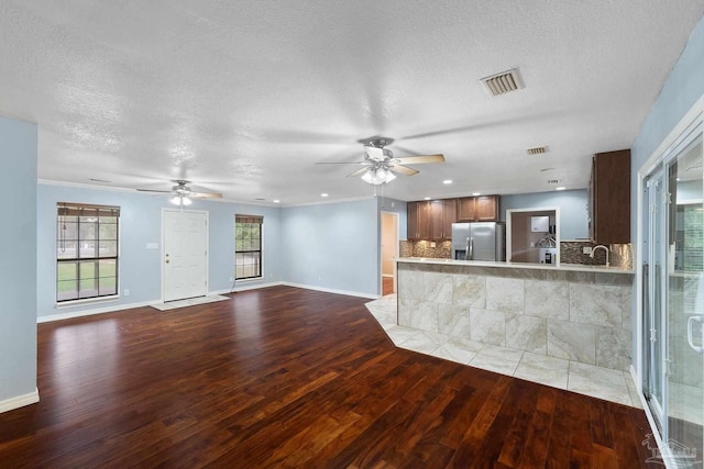 unfurnished living room with wood-type flooring, a textured ceiling, and ceiling fan