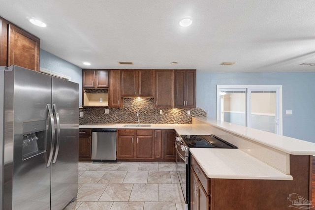 kitchen featuring sink, backsplash, kitchen peninsula, and appliances with stainless steel finishes