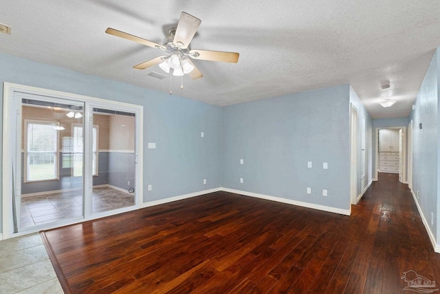 empty room with a textured ceiling, ceiling fan, and dark hardwood / wood-style flooring