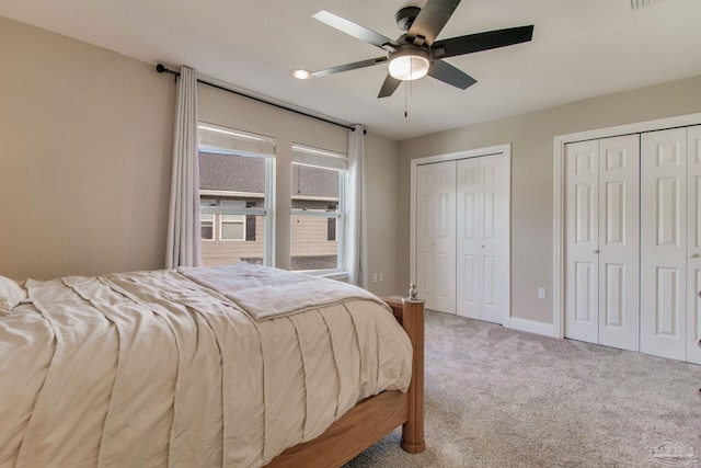 carpeted bedroom featuring ceiling fan and multiple closets