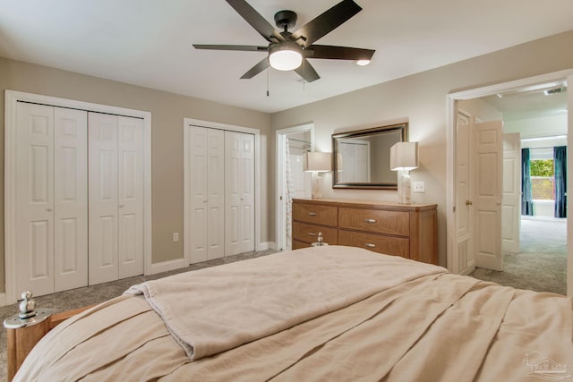 bedroom featuring light carpet, ceiling fan, and two closets