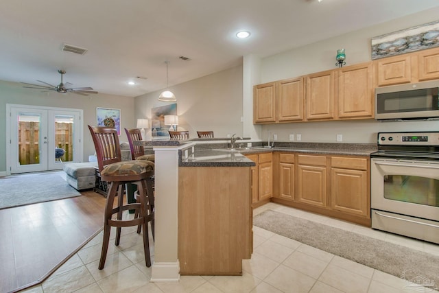 kitchen with french doors, hanging light fixtures, a kitchen bar, kitchen peninsula, and stainless steel appliances