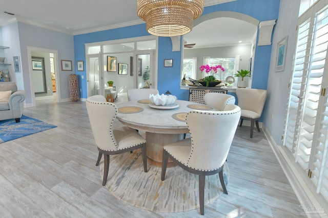 dining area featuring baseboards, visible vents, arched walkways, and light wood-style floors