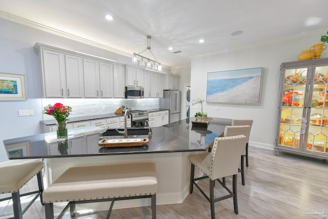 kitchen with dark countertops, a sink, a kitchen bar, and appliances with stainless steel finishes