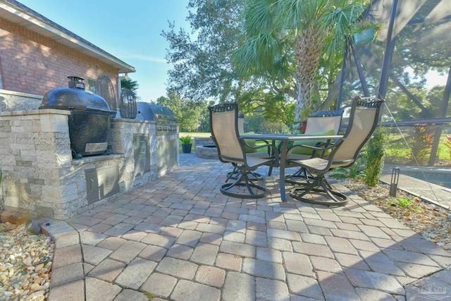 view of patio featuring an outdoor kitchen, outdoor dining area, glass enclosure, and area for grilling