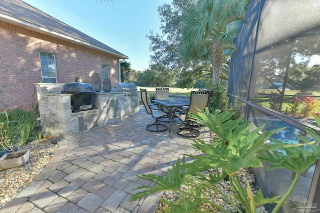view of patio with grilling area, an outdoor kitchen, outdoor dining area, and a lanai
