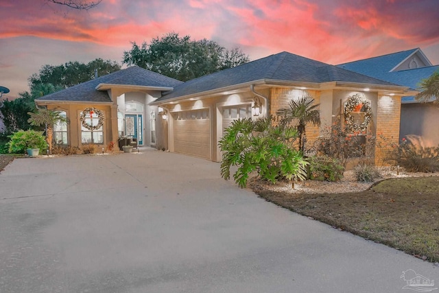 view of front of property featuring an attached garage, driveway, and roof with shingles