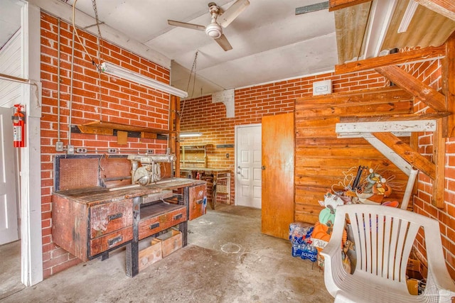 misc room with a workshop area, ceiling fan, brick wall, and concrete floors