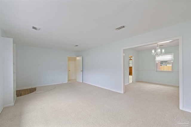 carpeted spare room featuring a notable chandelier