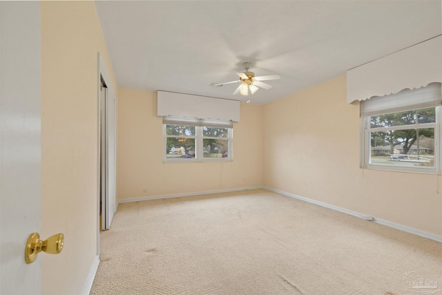 empty room featuring a wealth of natural light, ceiling fan, and light carpet