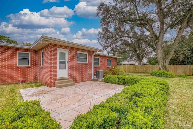 back of house with central AC unit, a yard, and a patio